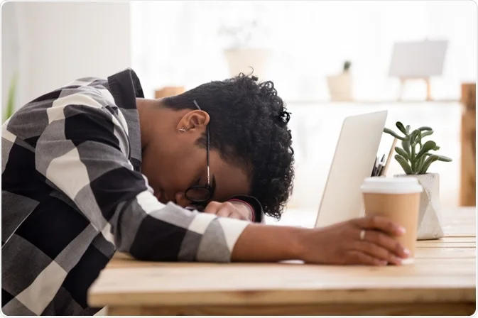 Person struggling with sleep deprivation while using phone at night, representing the health effects of sleeping less than 6 hours
